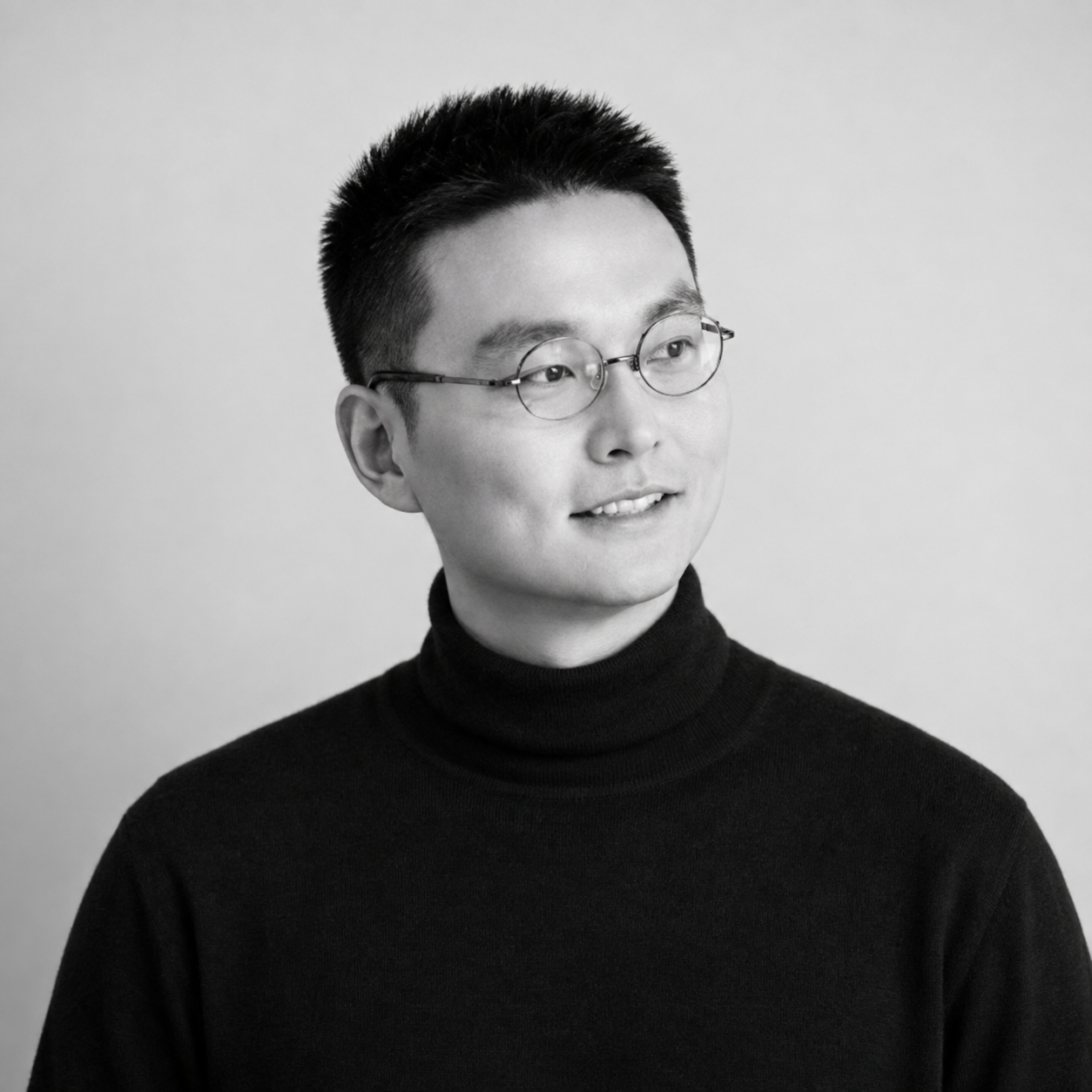 Yomin Ma, wearing round glasses and a black turtleneck
