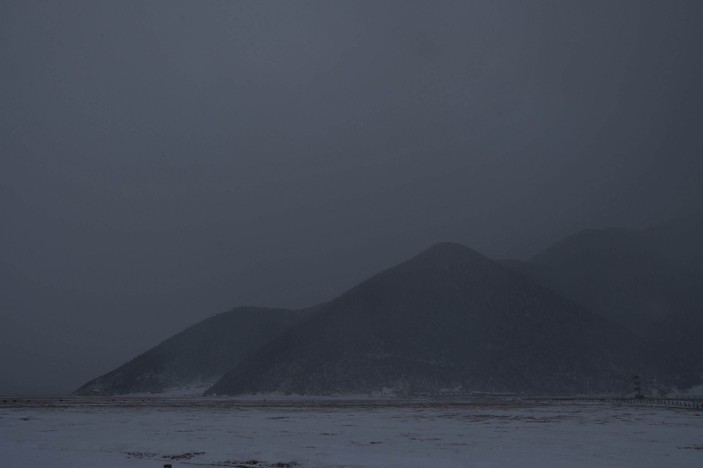 Snow-covered mountains under overcast sky on a vast plateau