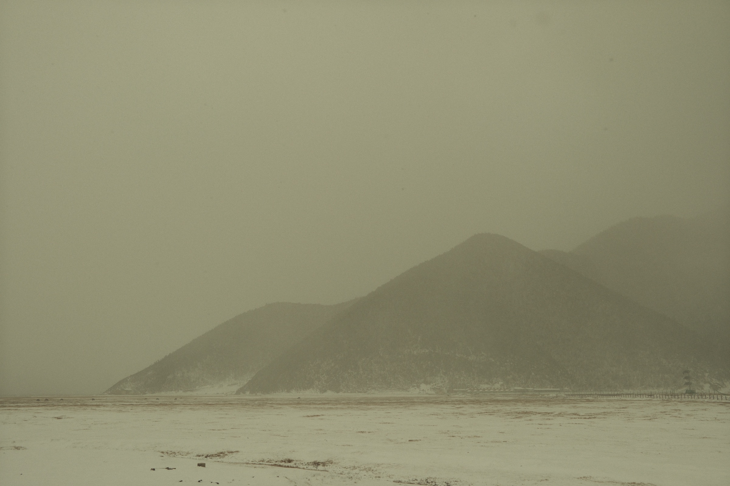 Misty mountain silhouettes rising above a snow-covered plain