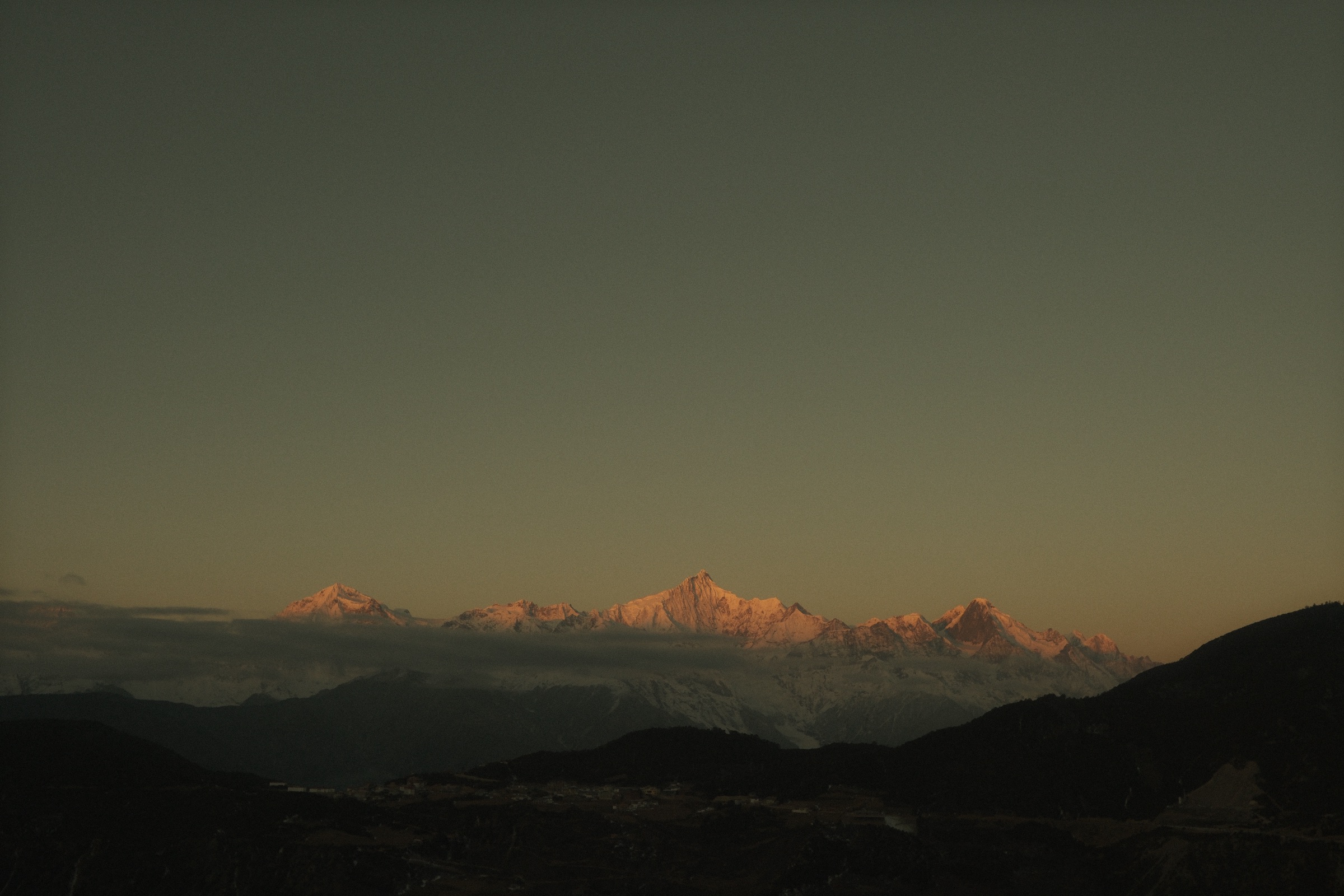 Golden sunrise light hitting Meili Snow Mountain peaks