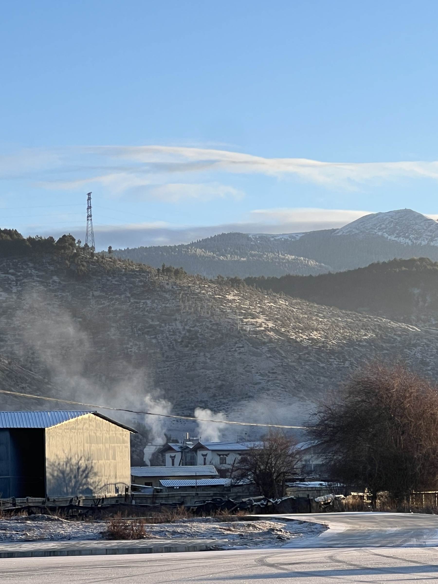 Mountain village in winter with rising smoke and snow-dusted hills